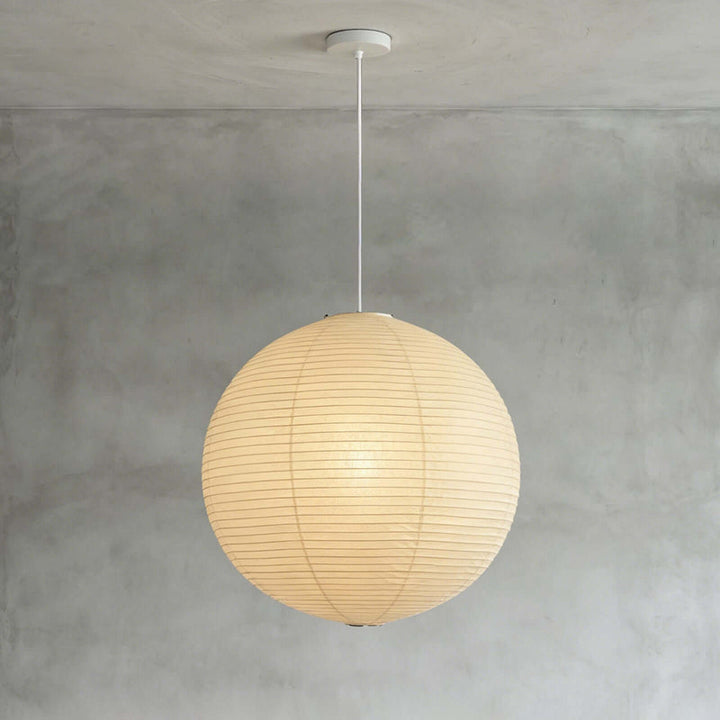 Spherical washi paper lamp with black hanging cord against matte grey interior wall