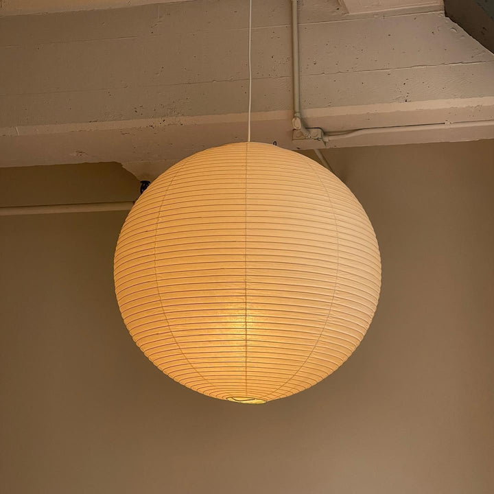 Multiple small washi paper spherical pendants hung above white modern kitchen island countertop