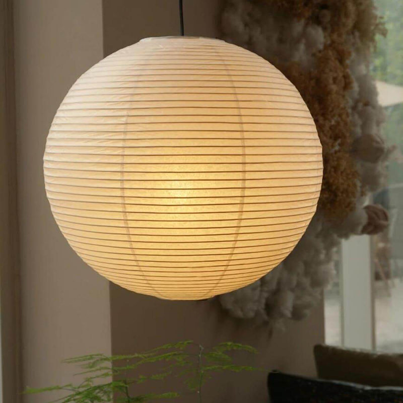 Warm glow washi paper spherical lamp over small wooden dining table set for two