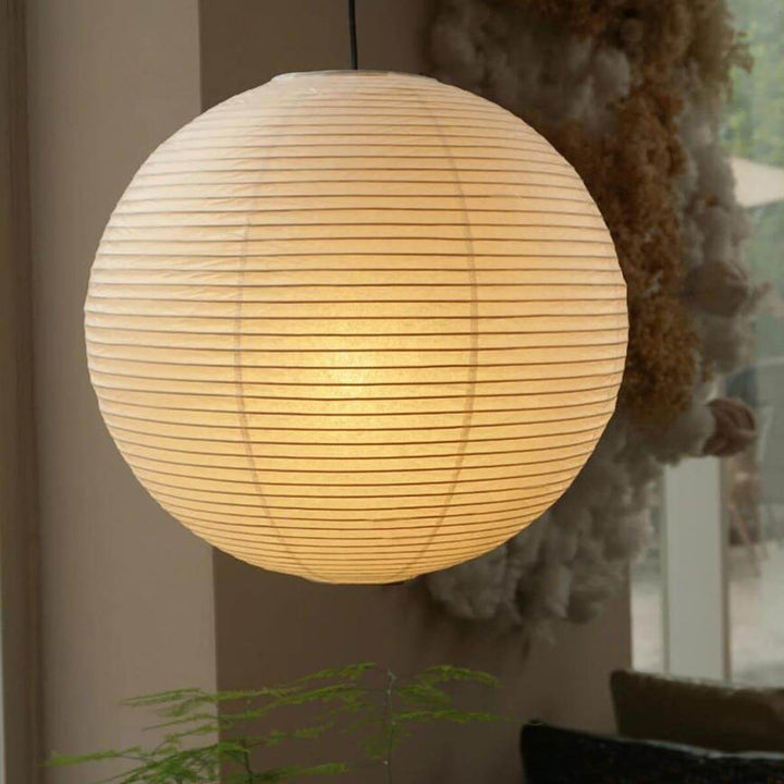 Warm glow washi paper spherical lamp over small wooden dining table set for two