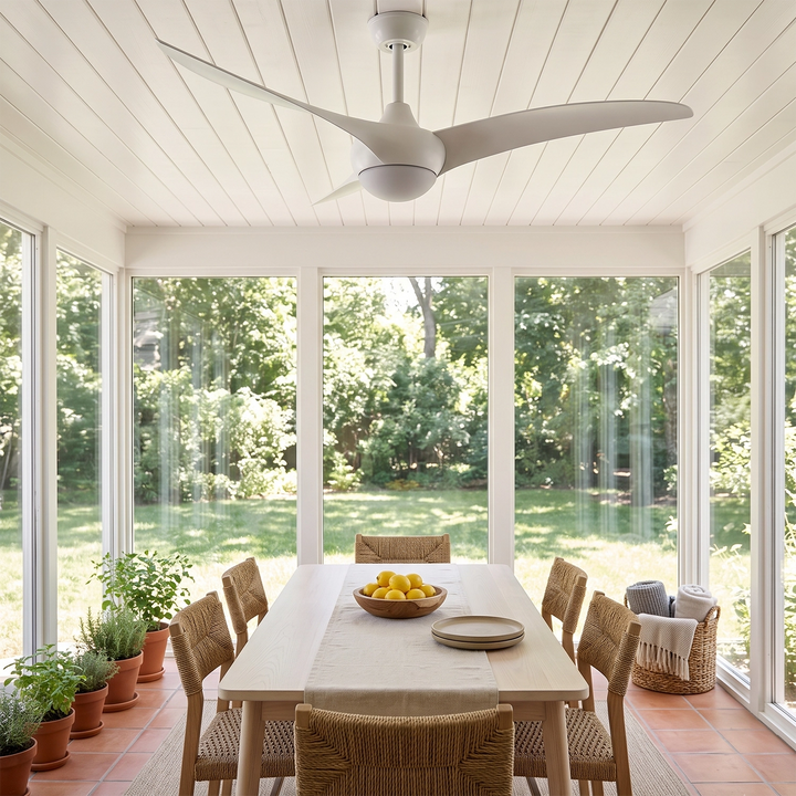White ceiling fan with light above a dining table in a glass walled sunroom